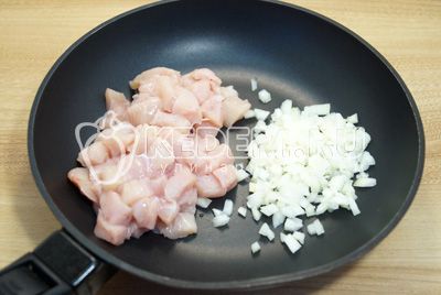 Na сковороде с двумя столовыми ложками растительного масла обжарить мелко нашинкованный лук и кубиками нарезанное куриное филе 3-5 минут.