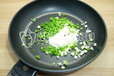 Na сковороде со сливочным маслом обжарить мелко нашинкованный зеленый лук.