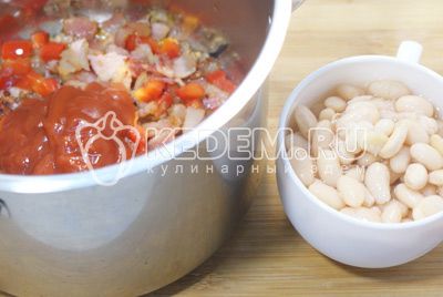 Adicionar в кастрюлю и добавить протертые помидоры «PODRAVKA» и консервированную белую фасоль. Залить бульоном и посолить. 
