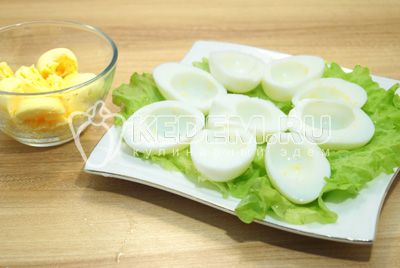 Wytnij на половинки, белки выложить на блюдо с листьями салата, желтки выложить в миску.